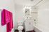 Bright and modern bathroom with elegant lighting, featuring plush pink towels, a pristine vanity, and a relaxing bathtub.