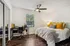 Bright and inviting bedroom with cozy bedding and stylish decor, featuring a modern ceiling fan and a sleek work desk by the window.