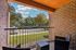 Charming balcony view with cozy seating overlooking a lush, landscaped parking area and vibrant greenery.