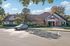 Charming apartment complex exterior with lush landscaping, ample parking, and a banner advertising 2, 3, and 4-bedroom units now leasing.