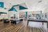 Chic recreational room with a sleek billiards table, modern shuffleboard, vibrant blue accent ceiling, and a view of the inviting outdoor pool.