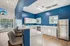 Sleek kitchen with vibrant blue walls, modern countertops, bar seating, and a large window offering a pool view.