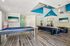 Vibrant game room featuring a sleek pool table, modern arcade games, and a stylish lounge area with large screen TVs and dynamic ceiling design.