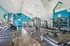 Inviting fitness center with modern gym equipment, bright turquoise walls, and vaulted ceilings, offering a vibrant workout atmosphere.