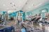Modern fitness center with state-of-the-art equipment, vibrant turquoise walls, and ample natural light enhancing an invigorating workout ambiance.