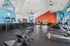 Vibrant and spacious gym with modern exercise equipment, featuring bright blue and orange accent walls, perfect for an energizing workout.