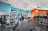 Vibrant fitness center with modern exercise equipment, bright blue and orange walls, and sleek flooring.