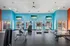 Vibrant fitness center with modern equipment, bright blue and orange walls, and natural light streaming through large windows.