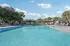 Inviting swimming pool with vibrant blue water surrounded by lounge chairs and lush palm trees, perfect for relaxation and leisure.