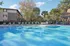 Inviting apartment complex pool surrounded by lounge chairs, lush trees, and a cozy gazebo for a perfect relaxation spot.
