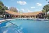 Inviting poolside view with elegant lounging chairs and a charming clubhouse under a bright blue sky.