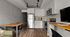 Modern kitchen and dining area featuring sleek white cabinetry, stainless steel appliances, and cozy wooden tables, perfect for entertaining or intimate meals.