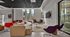 Modern lounge area with vibrant seating, large windows offering natural light, and a sleek wall-mounted TV.