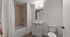 Contemporary bathroom with elegant beige tiles, modern fixtures, and a clean white vanity.