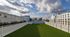Expansive rooftop terrace with lush green artificial grass, surrounded by modern cityscape views, perfect for relaxation and gatherings.