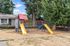 Inviting playground area featuring vibrant slides, swings, and a climbing wall surrounded by lush greenery.