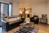 Inviting living room with black leather furniture, modern decor, and an open kitchen in the background.
