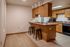 Warm kitchen area with wooden cabinets, a breakfast bar with two stools, and modern appliances.