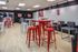 Inviting social lounge area with modern red and white high tables, surrounded by comfortable black seating.