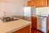 Cozy kitchen with warm wooden cabinets, a modern white refrigerator, and a charming electric stove, perfect for culinary creativity.