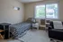 Cozy bedroom with a single bed, modern decor, and large window offering abundant natural light and views of lush greenery.