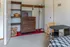 Cozy room with elegant wooden dresser, organized shelving, vibrant red carpet, and multifunctional workspace ideal for productivity.