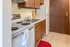 Cozy kitchen with warm wood cabinetry, modern appliances, and sleek countertops in a charming apartment setting.