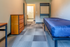 Modern apartment bedroom with cozy blue bed, stylish wooden dresser, and open walk-in closet, exuding a minimalist charm.