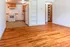 Inviting apartment with gleaming hardwood floors, well-lit kitchen featuring modern appliances, and ample built-in shelving.