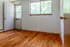 Bright, inviting room with hardwood floors, large window offering lush green views, and spacious layout perfect for personalization.