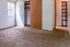 Bright and airy room with plush carpeting, featuring a spacious closet and a door leading to the outside, perfect for comfortable living.