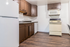 Charming kitchen with modern appliances, sleek brown cabinets, and polished hardwood floors, offering a cozy culinary space.