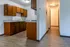 Warm and inviting kitchen area with rich wooden cabinets and sleek countertops, leading to a cozy hallway with elegant lighting.