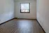 Bright and airy room with sleek wooden flooring and a large window offering natural light.
