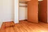 Warm, inviting apartment with rich wooden flooring and a spacious open closet.