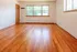 Bright, spacious living room with gleaming hardwood floors and large windows offering abundant natural light.