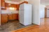 Charming apartment kitchen with warm wooden cabinetry, sleek countertops, and modern white appliances, opening to a spacious living area with inviting hardwood floors.