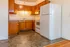 Charming kitchen with warm wood cabinetry, ample counter space, and modern white appliances on elegant tiled flooring.