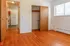 Cozy apartment interior with warm wood flooring, bright natural light, and a glimpse of the modern kitchen.