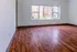Bright, spacious room with elegant wooden flooring and large windows offering a serene view of lush greenery.