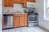 Charming kitchen with modern stainless steel appliances, warm wooden cabinets, and large window inviting natural light.