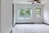 Bright and airy room with large window view, pristine tile flooring, and modern ceiling fan.