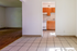 Charming apartment view with a sunlit tiled hallway leading to a cozy kitchen featuring warm wooden cabinets; adjacent is a spacious room with elegant wood flooring.
