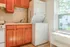 Bright kitchen space featuring warm wooden cabinetry, in-unit washer and dryer, and a scenic view from the large window.