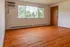 Bright and airy room with large window and elegant wooden flooring, perfect for cozy living.