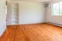 Bright and inviting room with elegant hardwood floors, a sleek wall-mounted air conditioner, and built-in shelving for ample storage.