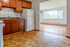 Inviting kitchen with warm wooden cabinets opening to a bright living area with large windows and lovely outdoor views.