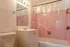 Bright, vintage-style bathroom featuring charming pink tiles, a sleek white vanity, and modern lighting.