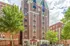 Charming red-brick apartment building with elegant architectural details, lush trees, and inviting street view.