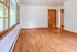 Bright living area with elegant wooden flooring, large picture window, and welcoming entrance, ready for your personal touch.
